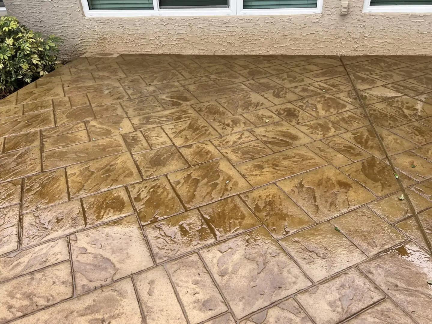 Ashlar slate stamped concrete patio in warm tan and grey, laid in a rectangular running pattern.